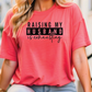 a woman wearing a pink shirt that says raising my husband is extraordinary