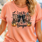 A woman wearing a pink t-shirt with a graphic design featuring a bow, pumpkins, and text that says "I put the BOO in BOUJEE".
