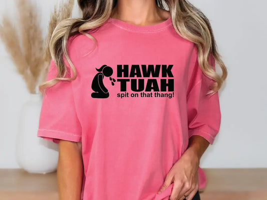 a woman wearing a pink t - shirt with the words hawk tuah on it