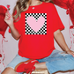 a woman sitting on a stool with a heart on her t - shirt