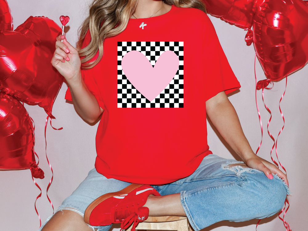 a woman sitting on a stool with a heart on her t - shirt