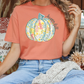 a woman sitting on a couch wearing a pumpkin t - shirt