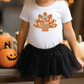 a little girl wearing a white shirt with a turkey on it