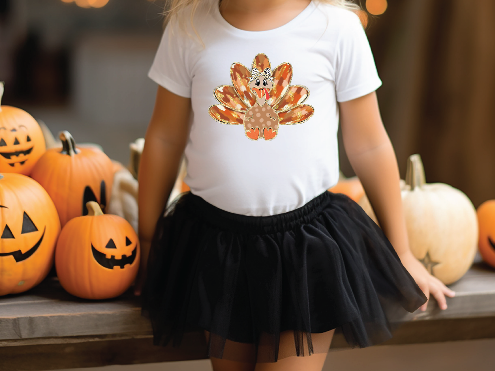 a little girl wearing a white shirt with a turkey on it