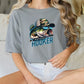 a woman sitting on a bed with a fish t - shirt on