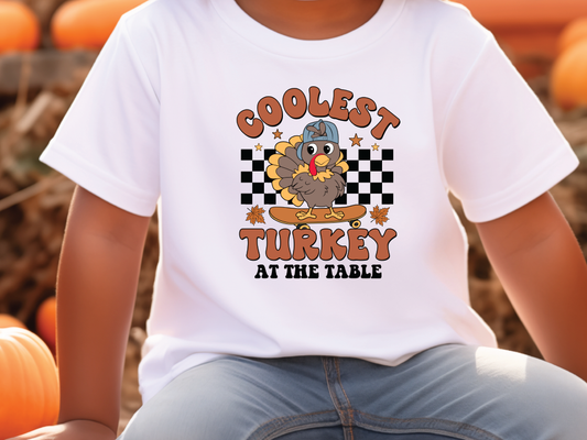 a young boy sitting on a pumpkin wearing a turkey t - shirt