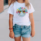 a little girl wearing a white shirt and denim shorts