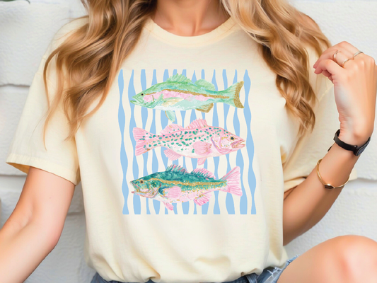 A woman wearing a white t-shirt with a graphic design of three colorful fish.