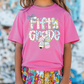 a little girl wearing a pink shirt and colorful shorts