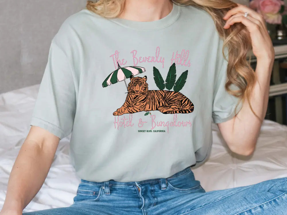 a woman sitting on a bed wearing a t - shirt with a tiger on it