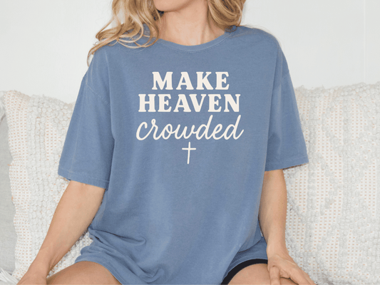 A woman wearing a blue t-shirt with the text "MAKE HEAVEN CROWDED" printed on it.