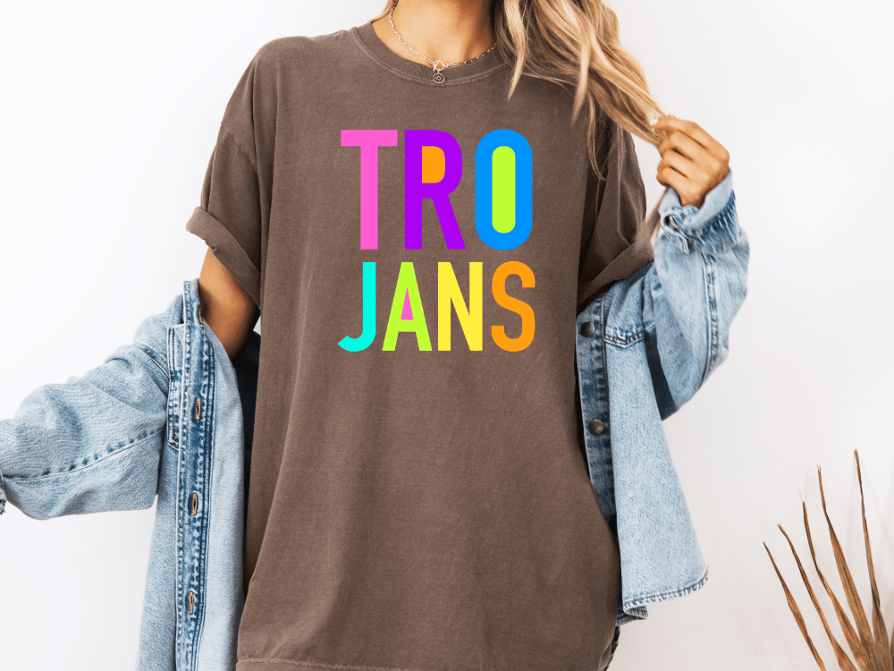 A person wearing a brown t-shirt with the text "TRO JANS" in a colorful font, paired with a denim jacket.