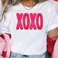 a woman wearing a white shirt with the word xoxo printed on it