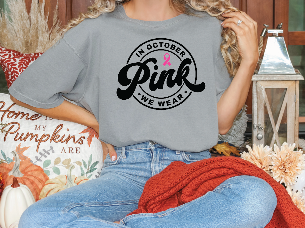 a woman sitting on a couch wearing a pink ribbon t - shirt