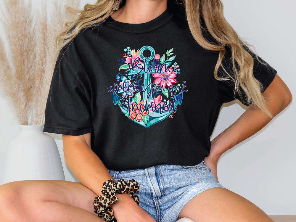 a woman sitting on a chair wearing a t - shirt with an anchor and flowers