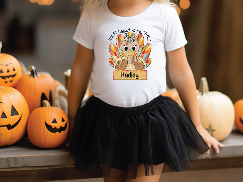 a little girl wearing a white shirt with a turkey on it