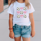 a little girl wearing a t - shirt with soccer balls on it