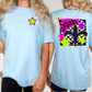 two women wearing light blue t-shirts with colorful designs on the back.