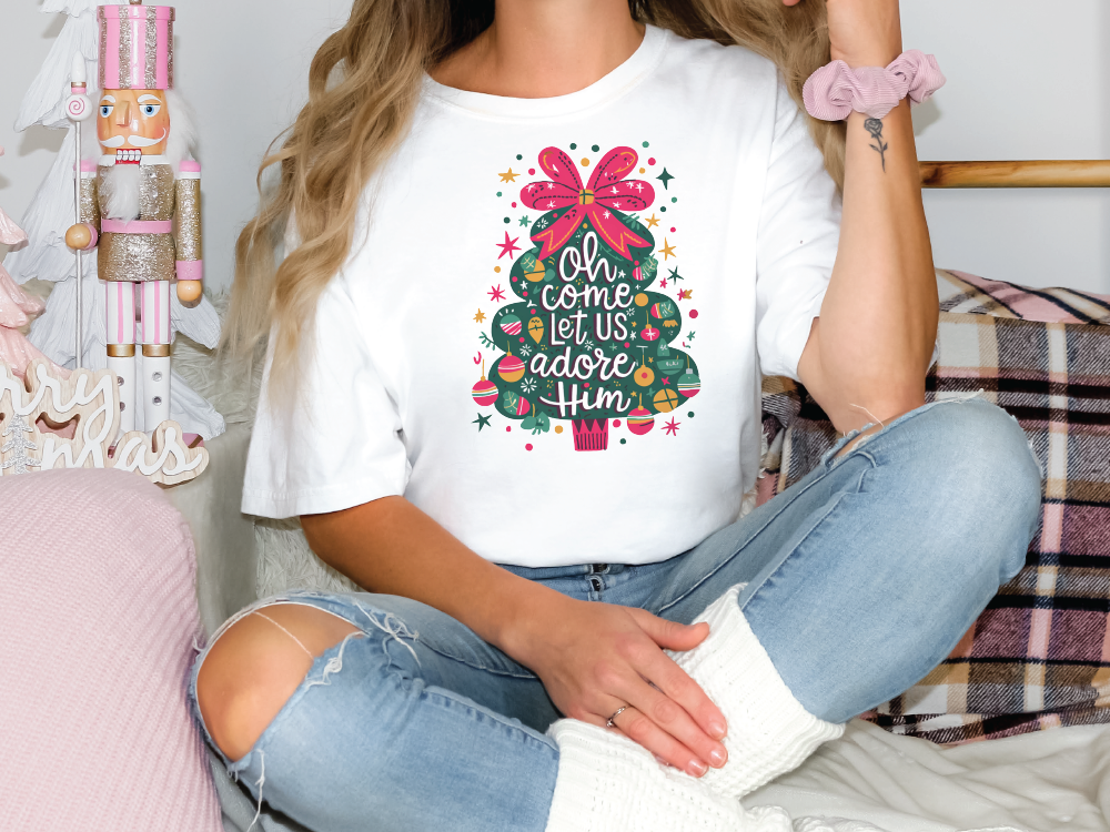 a woman sitting on a bed wearing a t - shirt with a christmas tree on