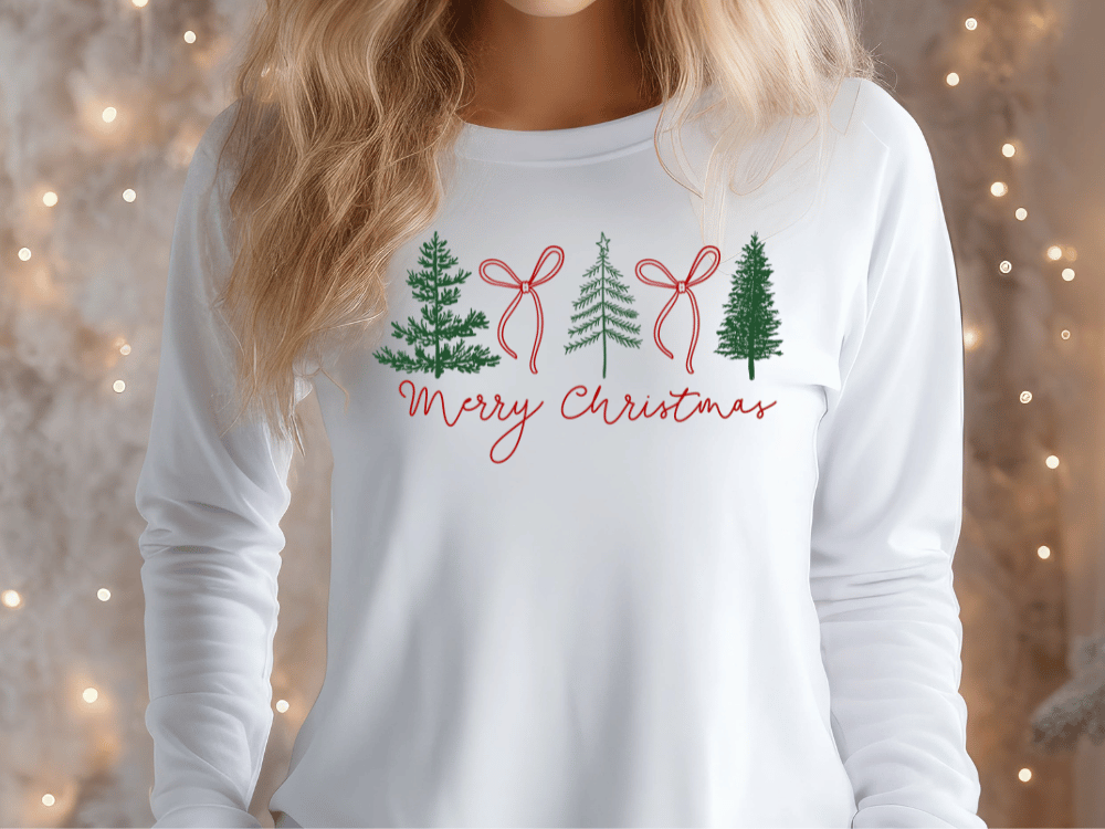 A woman wearing a white long-sleeved shirt with a Christmas tree design and the text "Merry Christmas" printed on it.