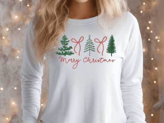 A woman wearing a white long-sleeved shirt with a Christmas tree design and the text "Merry Christmas" printed on it.