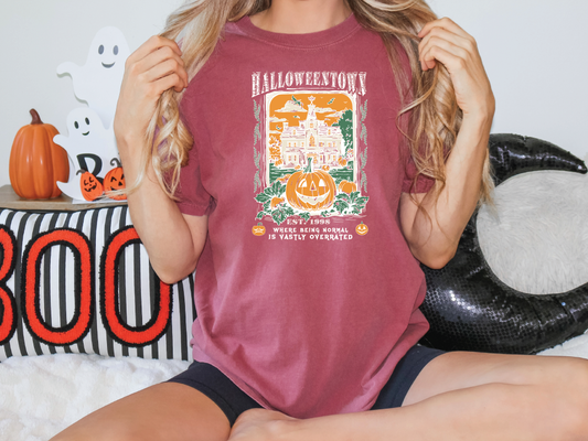 a woman sitting on a bed holding a halloween t - shirt