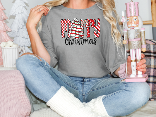 a woman sitting on a bed holding a christmas t - shirt