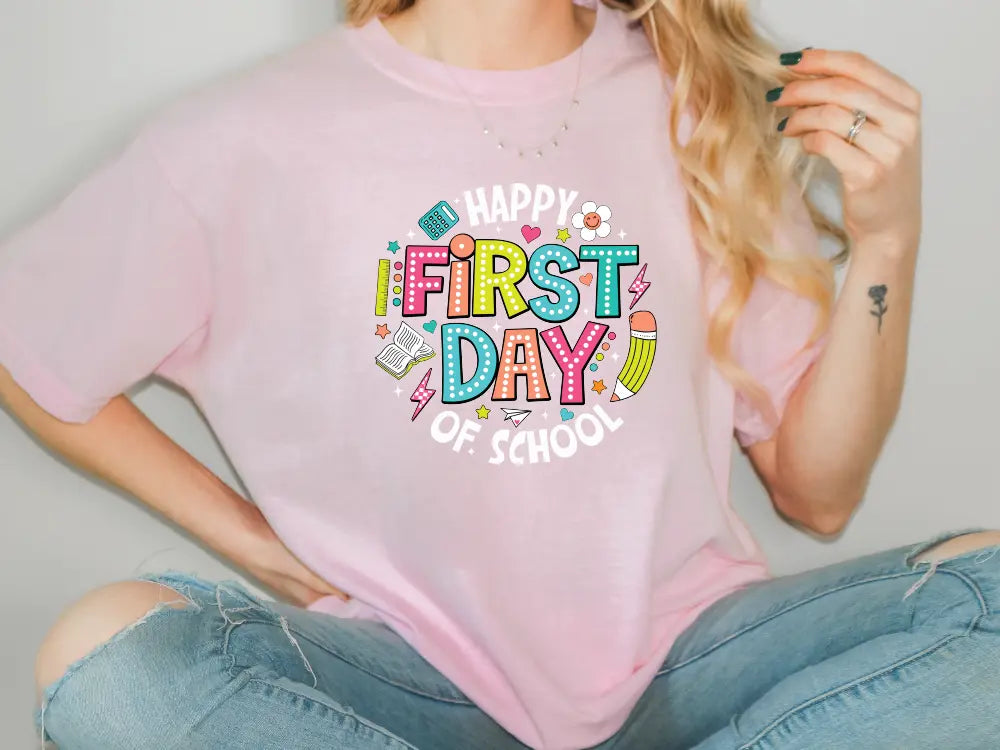 a woman wearing a pink shirt with the words happy first day of school on it