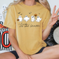 A person wearing a yellow t-shirt with a graphic of ghost characters and the text "Tis the season" is sitting on the floor.