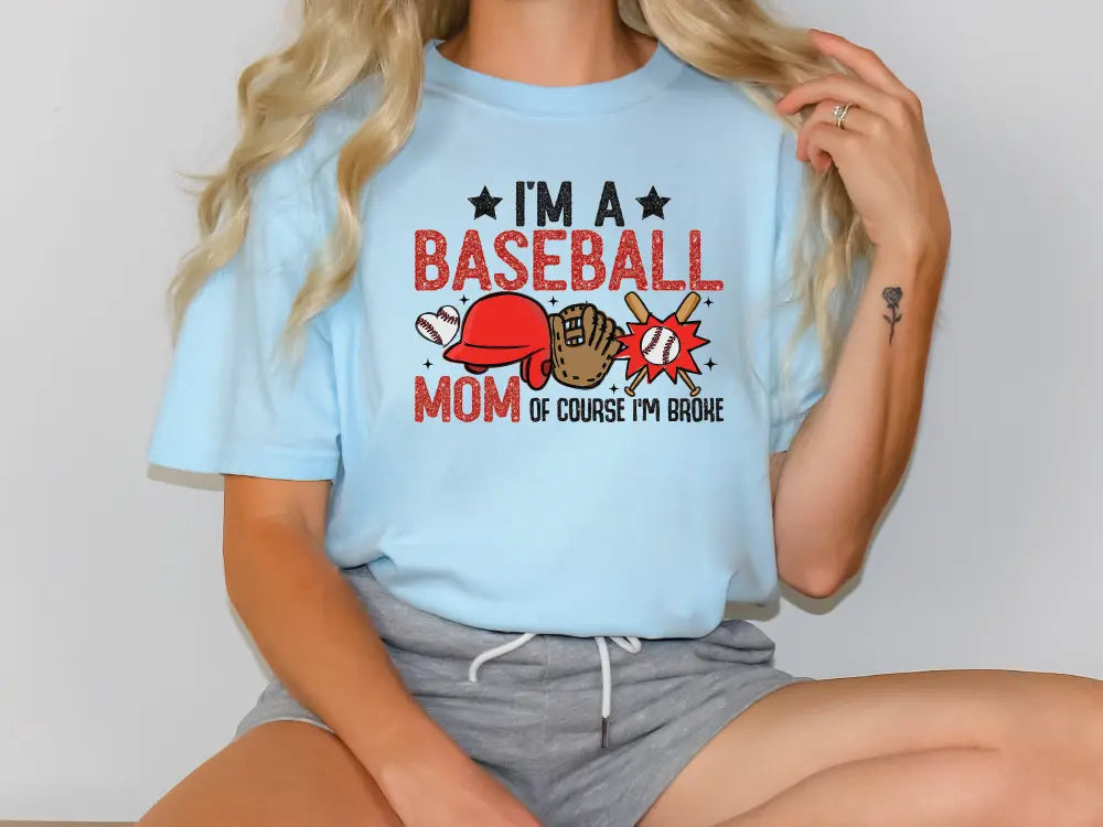 a woman sitting on a table wearing a baseball mom t - shirt