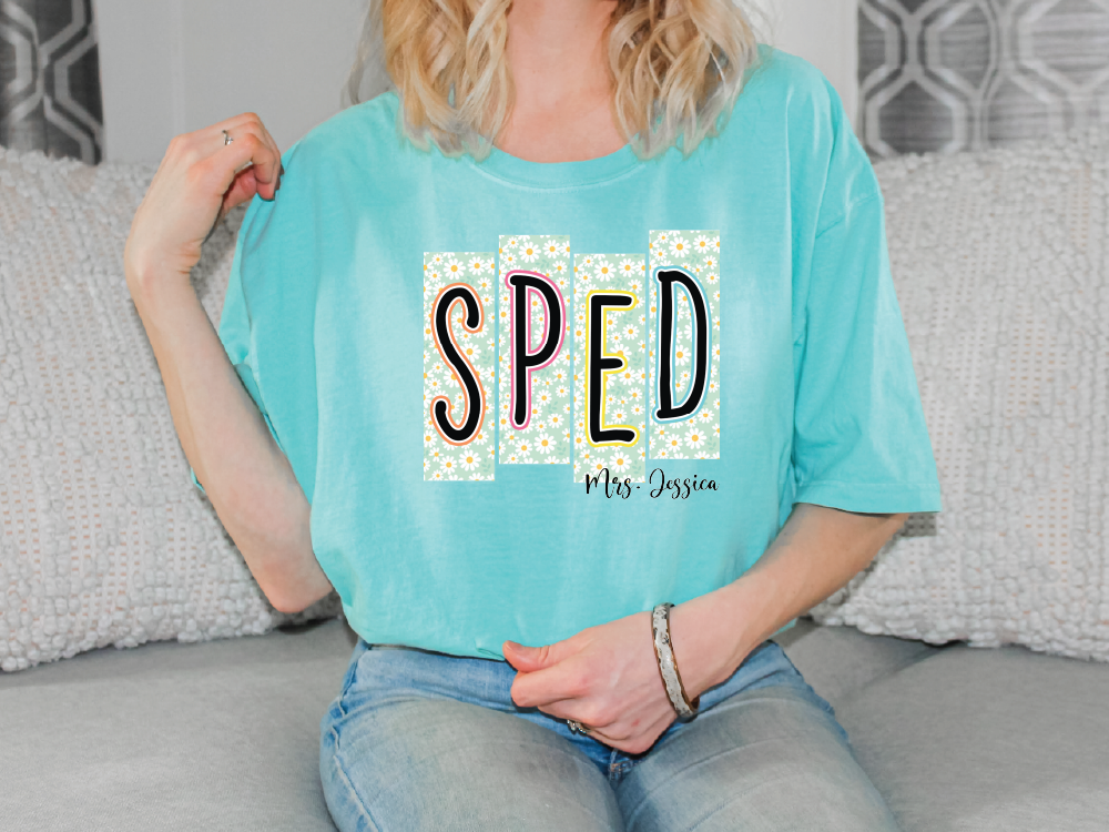 A woman wearing a turquoise t-shirt with the word "SPED" printed on it, sitting on a couch.