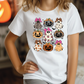 A person wearing a white t-shirt with a graphic design of various Halloween-themed characters, including pumpkins, ghosts, and bats.