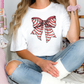 a woman sitting on a bed wearing a t - shirt with a bow on it