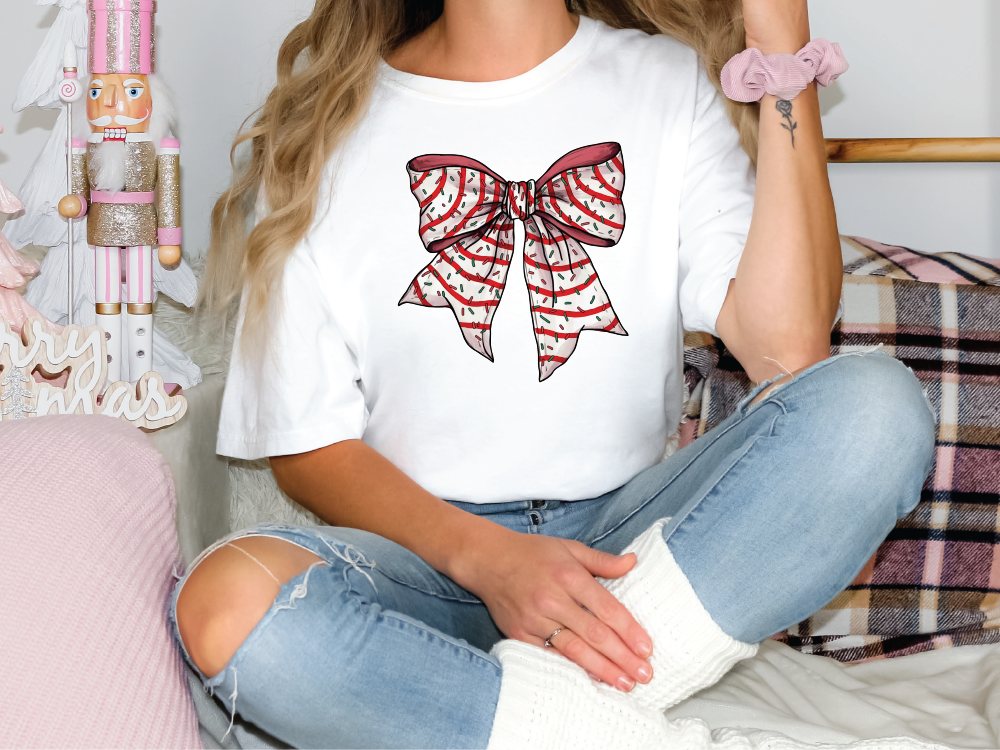 a woman sitting on a bed wearing a t - shirt with a bow on it