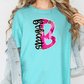 A woman wearing a turquoise t-shirt with a graphic design and a denim jacket.