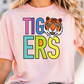 A woman wearing a pink t-shirt with the word "TIGERS" printed on it, featuring a tiger's face.
