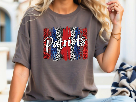 A woman wearing a gray t-shirt with the word "Patriots" printed on it, along with a patriotic design featuring red, white, and blue colors.