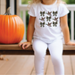 a little girl sitting on a bench next to a pumpkin