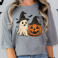 A woman wearing a gray t-shirt with a Halloween-themed graphic design featuring a ghost and a jack-o-lantern.