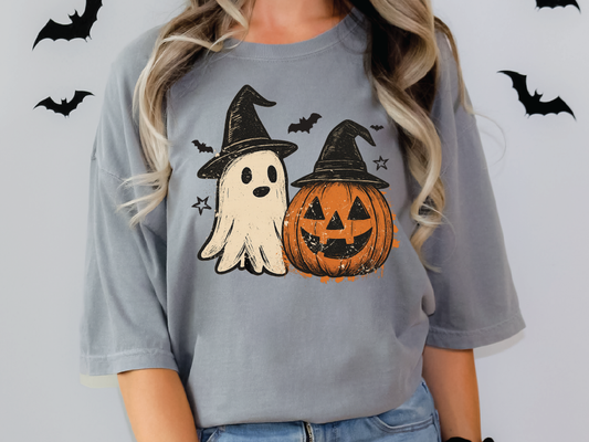 A woman wearing a gray t-shirt with a Halloween-themed graphic design featuring a ghost and a jack-o-lantern.