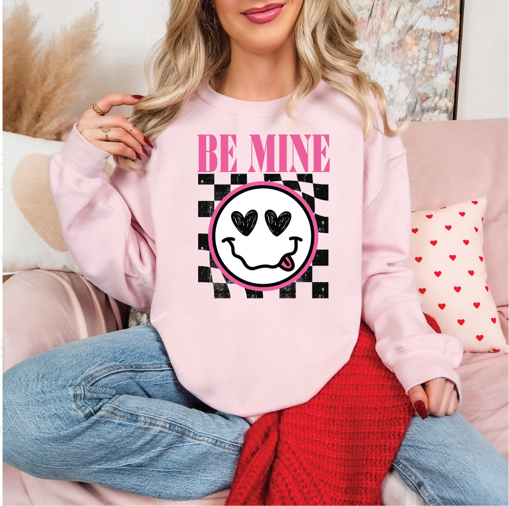 a woman sitting on a couch wearing a pink sweatshirt