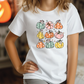 a little girl wearing a white shirt with pumpkins on it