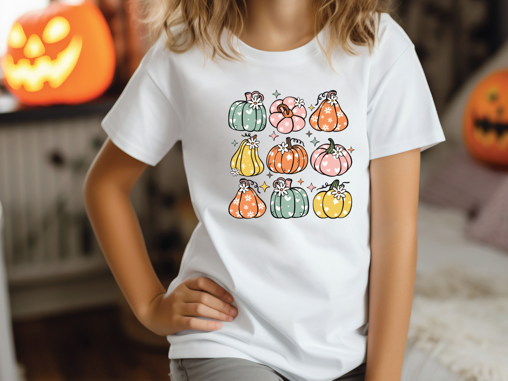 a little girl wearing a white shirt with pumpkins on it