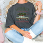 a woman sitting on a bed with a christmas tree on her shirt