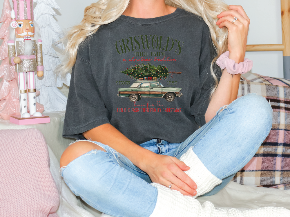 a woman sitting on a bed with a christmas tree on her shirt