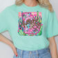 a woman wearing a green t - shirt with a picture of a snake on it