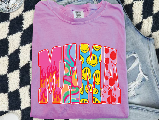 A pink t-shirt with the word "MAMA" printed on it, featuring colorful and abstract designs.