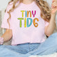 a girl sitting on a couch wearing a tiny tide shirt