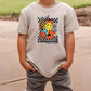 a young boy standing on a sidewalk wearing a t - shirt