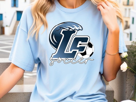 A woman wearing a light blue t-shirt with a graphic design featuring a soccer ball and the letters 'LF' printed on it.